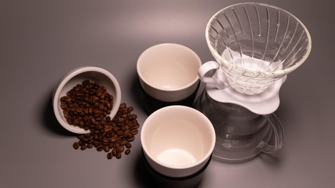 Pour-over dripper and cups beside coffee beans
